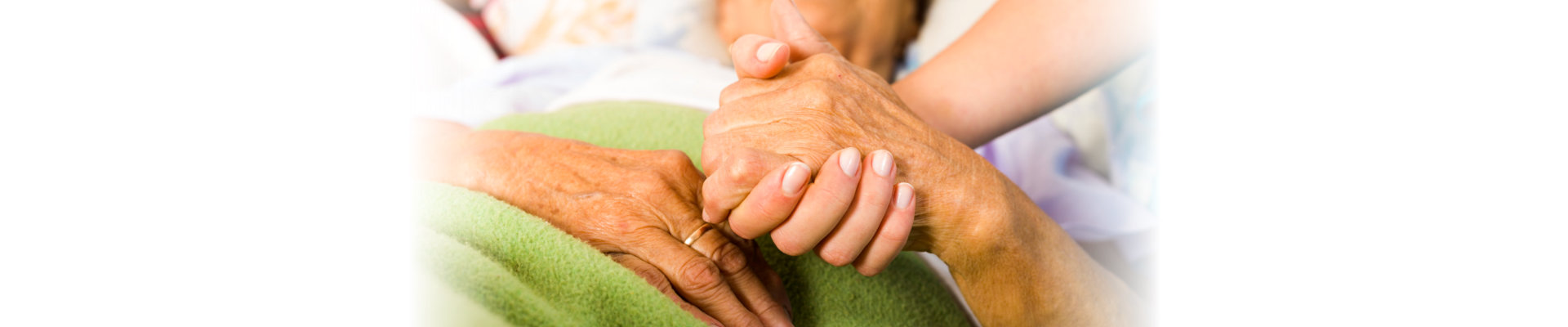 hands of a senior woman held tight by a caregiver